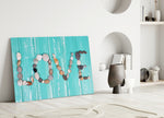 Close-up detail of LOVE spelled in stones and shells on turquoise wood