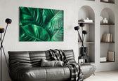 Green Tropical Leaf glass wall art styled above a sofa in a plant-filled living room