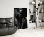 Woman glass wall art styled above a bed in a black-and-gold bedroom