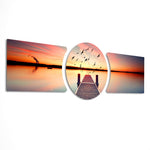 A wooden pier reaching into a calm lake at sunset with a flock of birds taking flight across a fiery orange sky. 3 piece glass wall art set E