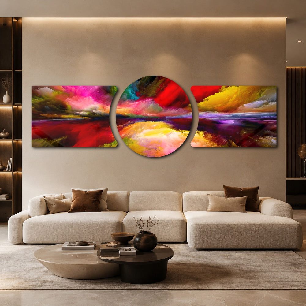 An abstract painterly skyscape of vivid red, pink, yellow and purple clouds sweeping over a glowing horizon and its reflection. 3 piece glass wall art set B