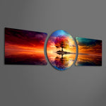 A vivid multicolored tree standing on a small island, perfectly mirrored in calm water beneath a blazing sunset sky. 3 piece glass wall art set E
