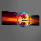 A vivid multicolored tree standing on a small island, perfectly mirrored in calm water beneath a blazing sunset sky. 3 piece glass wall art set E