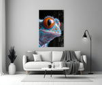 Close-up detail of turquoise gecko with marigold eye behind glass