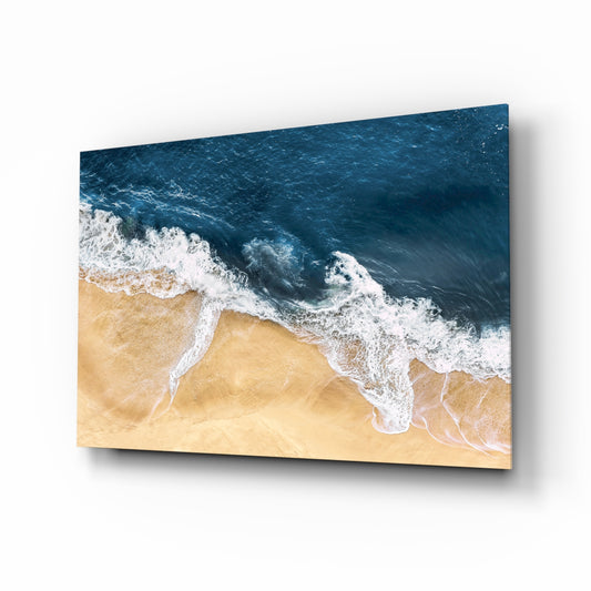 Aerial beach wave drone glass wall art above linen sofa in coastal living room