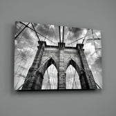 Brooklyn Bridge close-up showing Gothic arches and suspension cables under cloudy sky