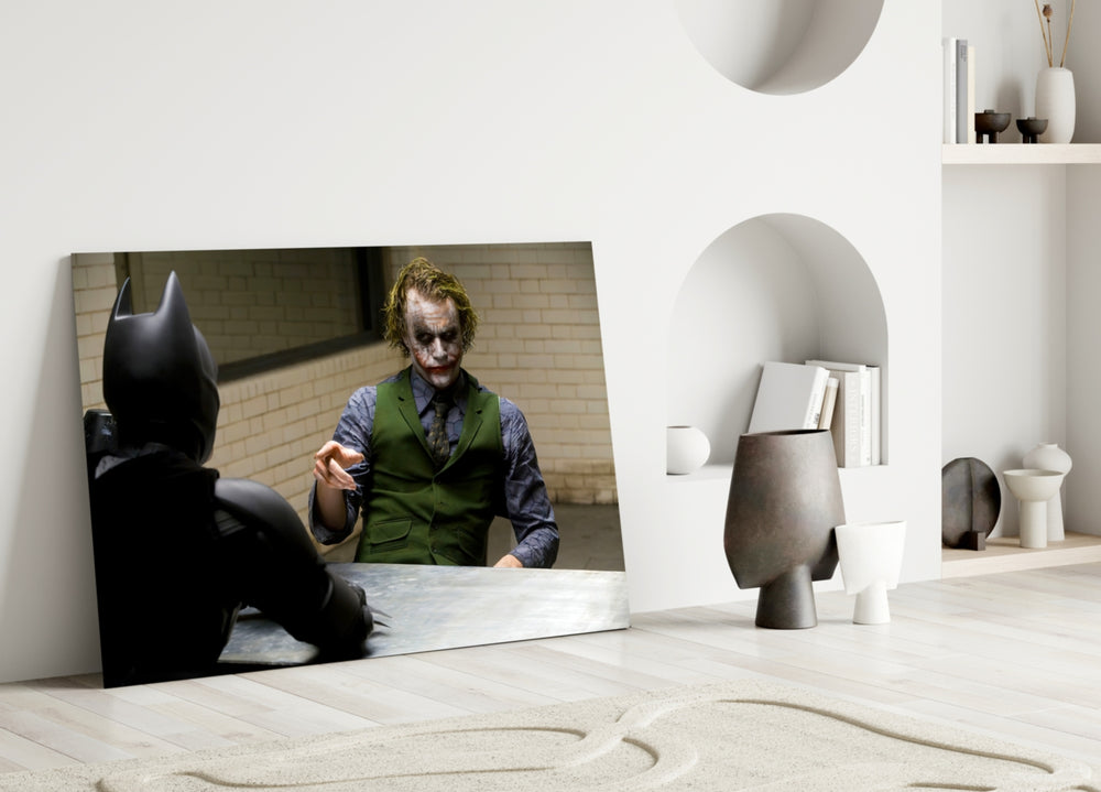 Interrogation close-up showing the Joker leaning toward Batman across cell-block table