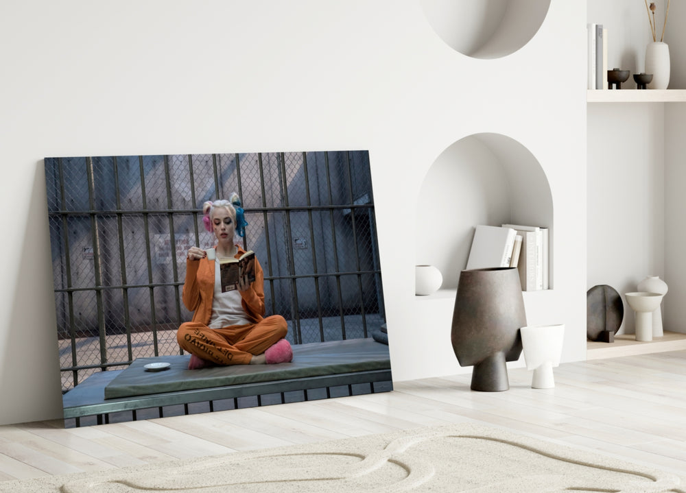 Harley Quinn close-up showing pigtailed heroine reading on prison mattress in cage