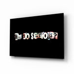 Why so Serious glass wall art displayed above a charcoal sofa in a slate-walled office lounge with steel desk and matte-black shelving