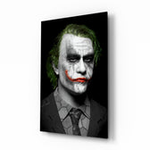 Joker glass wall art displayed above a black leather sofa in a moody home theater with brass arc lamp and reclaimed-wood console