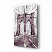 Brooklyn Bridge glass wall art displayed above a linen bed in a dusk-mauve bedroom with rattan nightstands and brushed-brass sconces