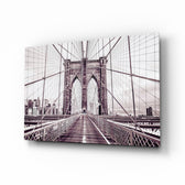 Brooklyn Bridge glass wall art displayed above a linen sofa in a beige living room with rattan armchair and walnut console