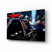 Joker glass wall art displayed above a black leather sectional in a moody home theater with brass arc lamp and reclaimed-wood console