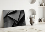Close-up detail of folded triangular planes in charcoal monochrome