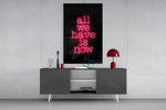 All We Have Is Now glass wall art catching light to reveal its painted glow