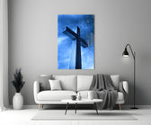 Close-up detail of stone cross in cobalt rain behind glass