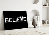 Close-up detail of glowing Believe stencil behind glass